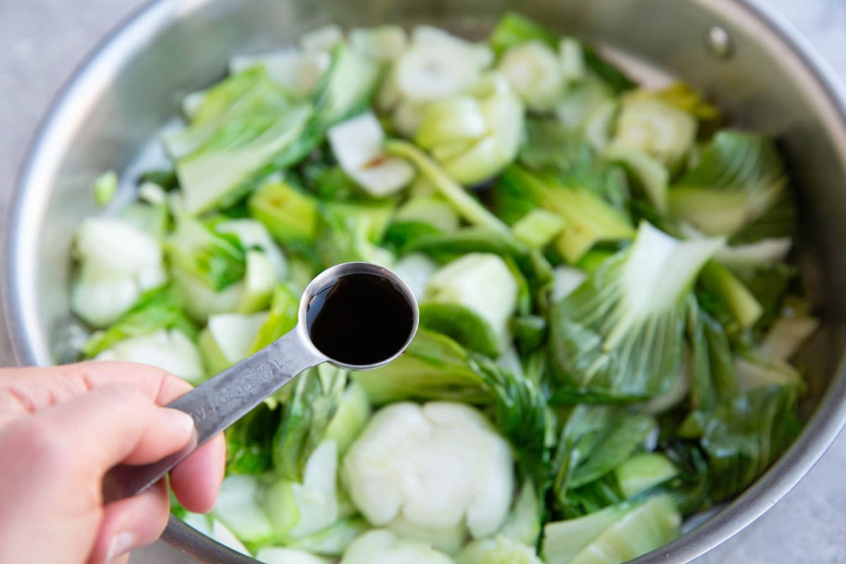 Pour the soy sauce into the skillet with the vegetables.