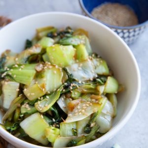Bowl full of baby bok choy with sesame seeds sprinkled on top.