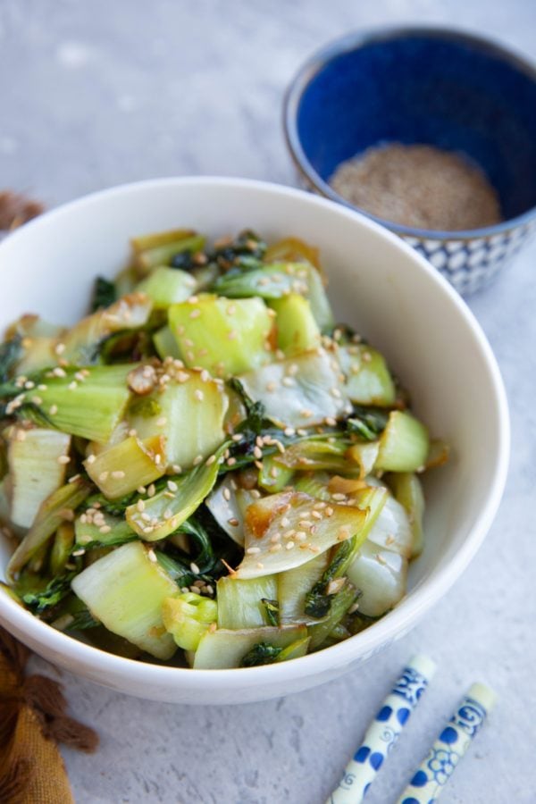 Bowl full of baby bok choy with sesame seeds sprinkled on top.