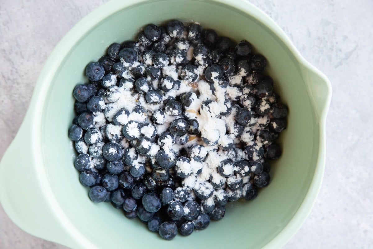 Mixing bowl full of blueberries, flour, and pure maple syrup to make blueberry filling.
