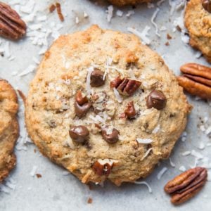 Cookies on a cookie sheet with pecans, chocolate chips, and shredded coconut.