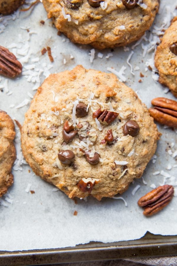 Cookies on a cookie sheet with pecans, chocolate chips, and shredded coconut.