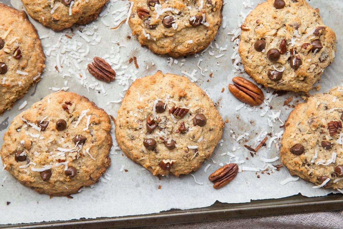 Baking sheet full of cowboy cookies with pecans sprinkled around.