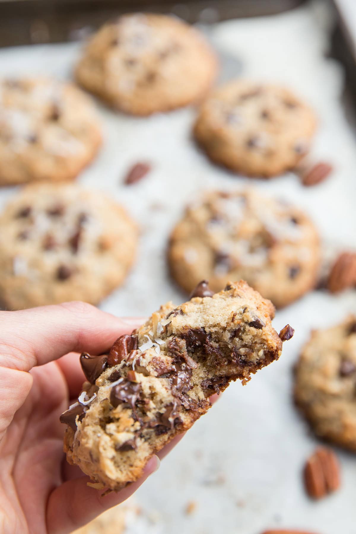 Hand holding a cookie with a bite taken out to see the gooey chocolate inside.