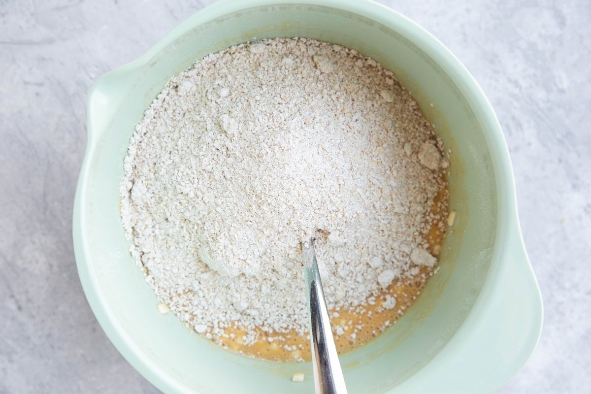 Mixing bowl with wet ingredients on the bottom and dry ingredients on top to make cottage cheese quick bread.
