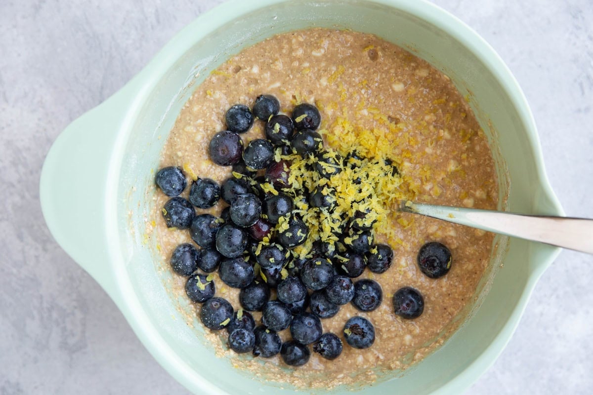 Mixing bowl with cottage cheese bread batter with blueberries on top and lemon zest.