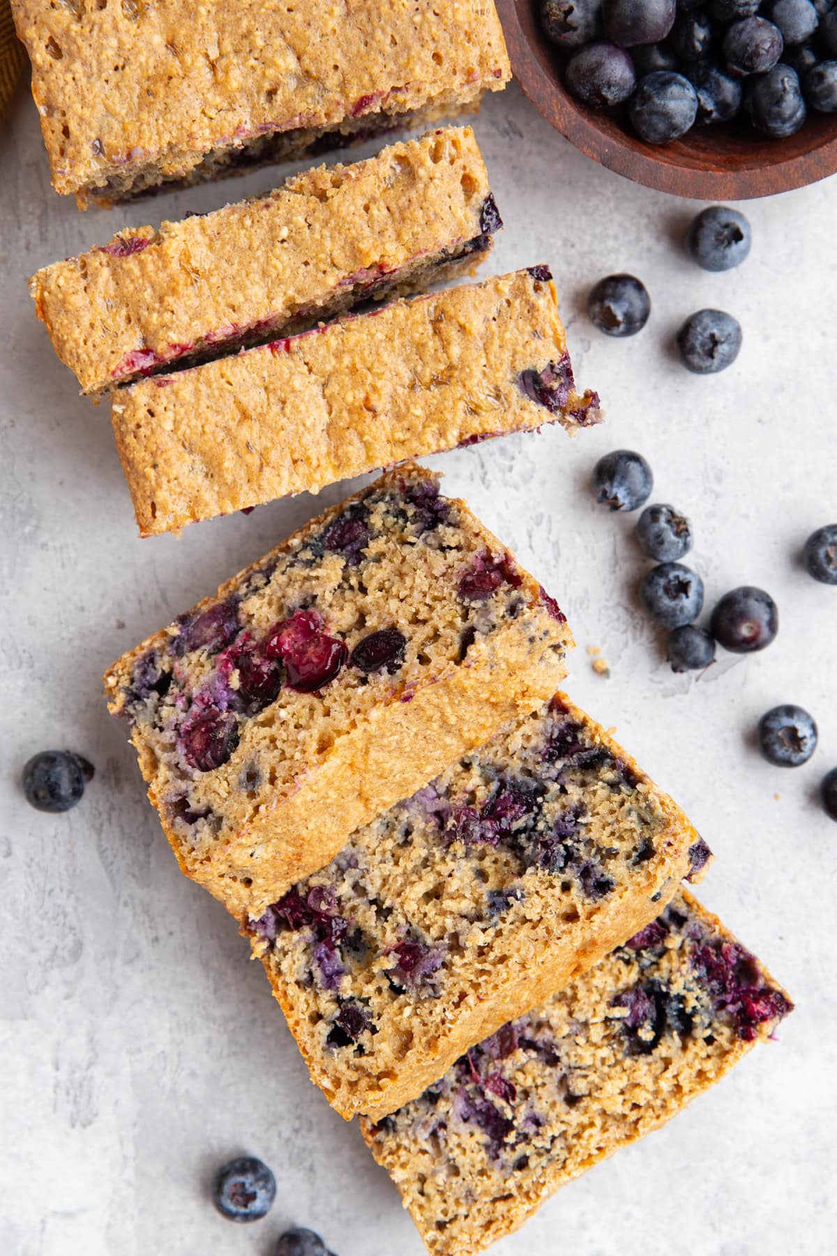Loaf of cottage cheese bread on a background, cut into individual slices with fresh berries all around.