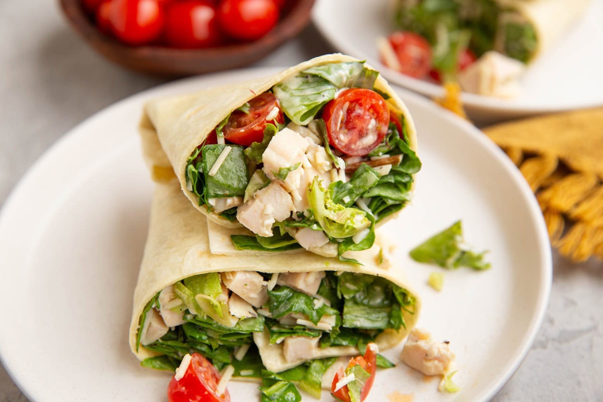 Plate of salad wraps with another plate of wraps in the background.