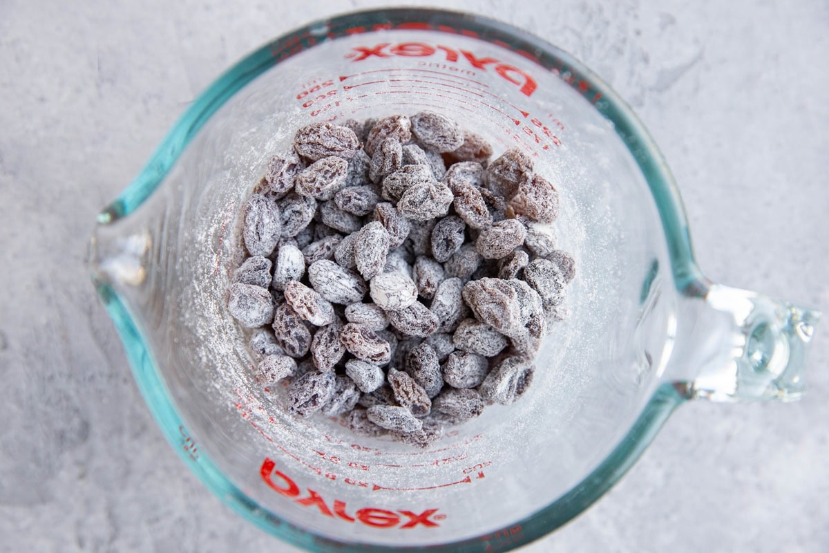 Raisins tossed in flour in a measuring cup.