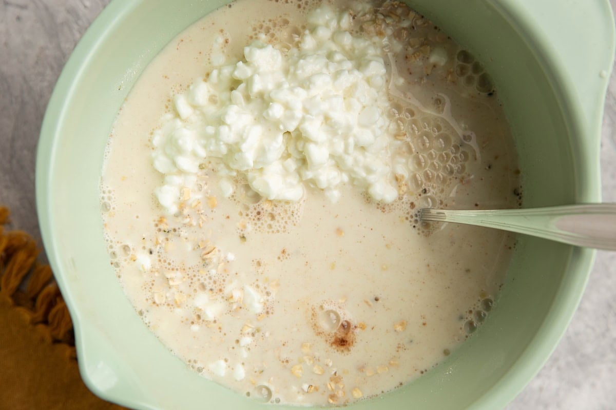 Wet ingredients on top of dry ingredients in a mixing bowl to make overnight oats.