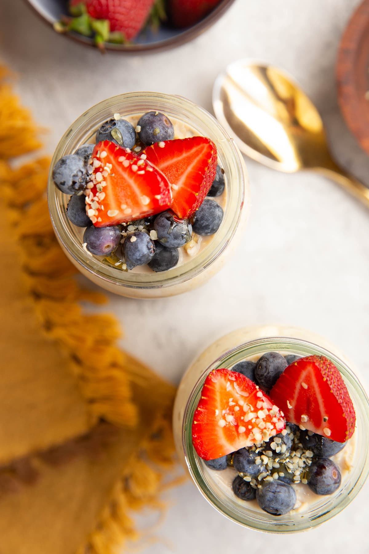 Two glasses filled with cottage cheese overnight oats with fresh fruit on top.