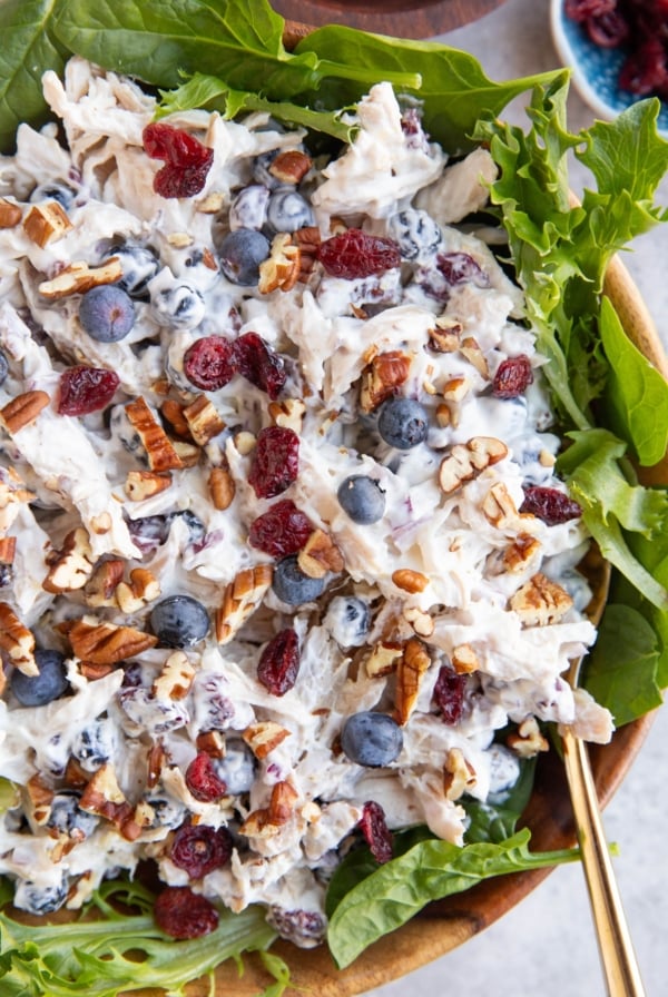 large wooden bowl full of chicken salad on a bed of lettuce.