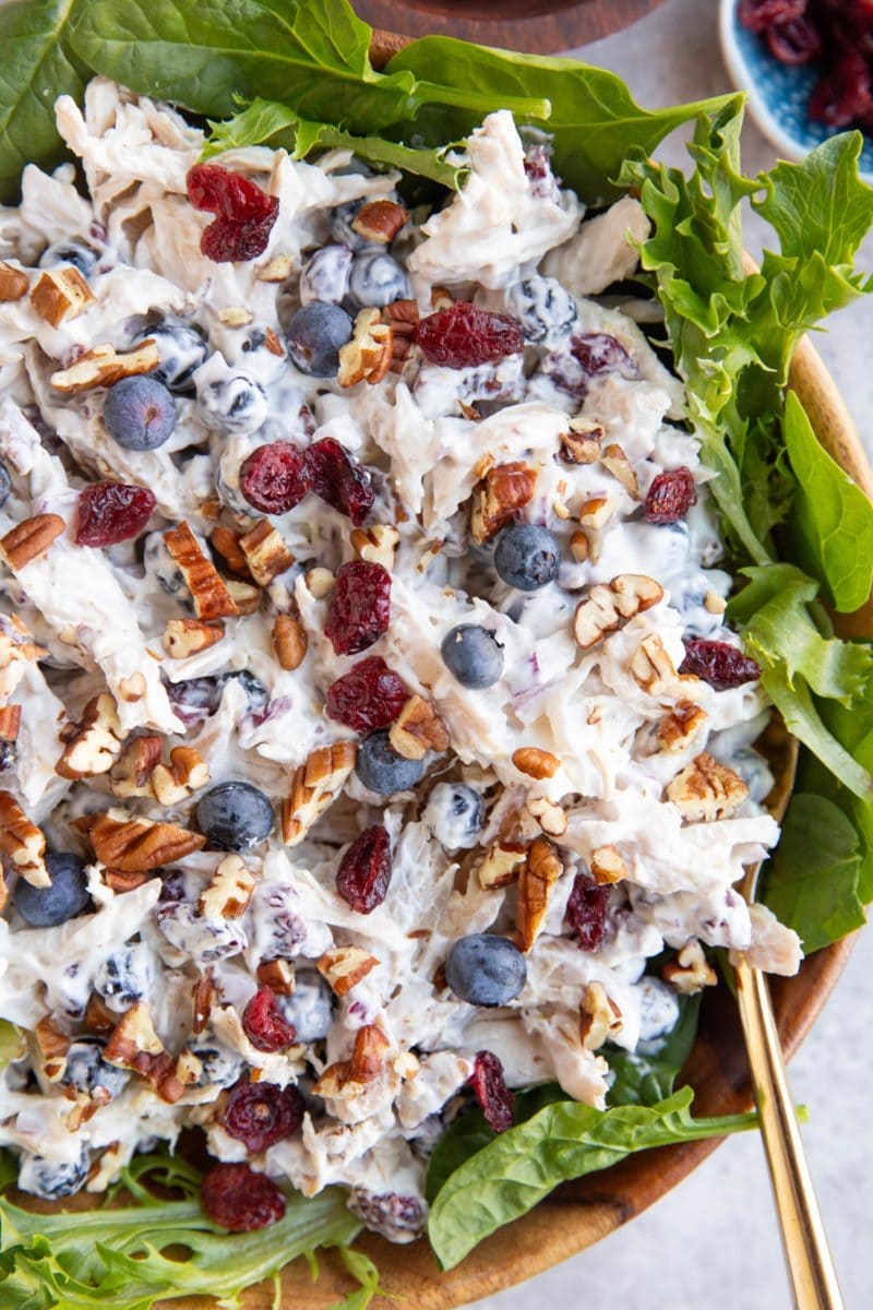 large wooden bowl full of chicken salad on a bed of lettuce.