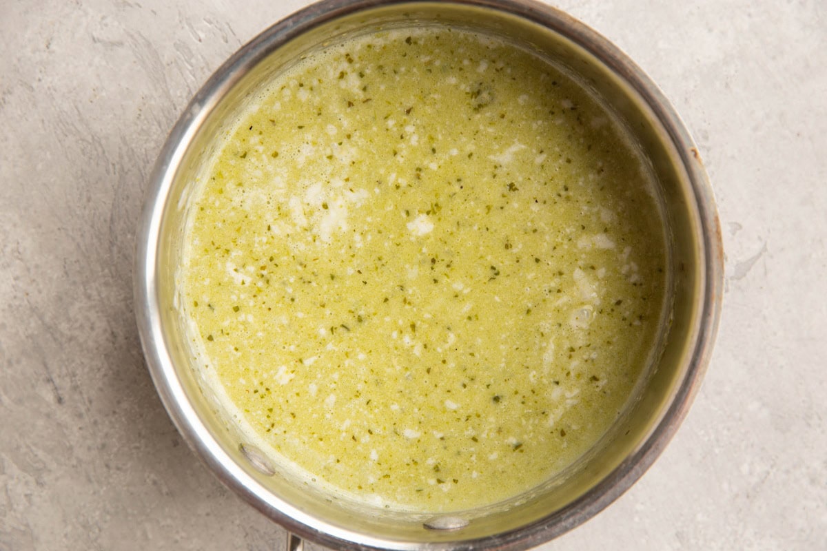 Pot full of coconut milk and pesto sauce for creamy pesto sauce.