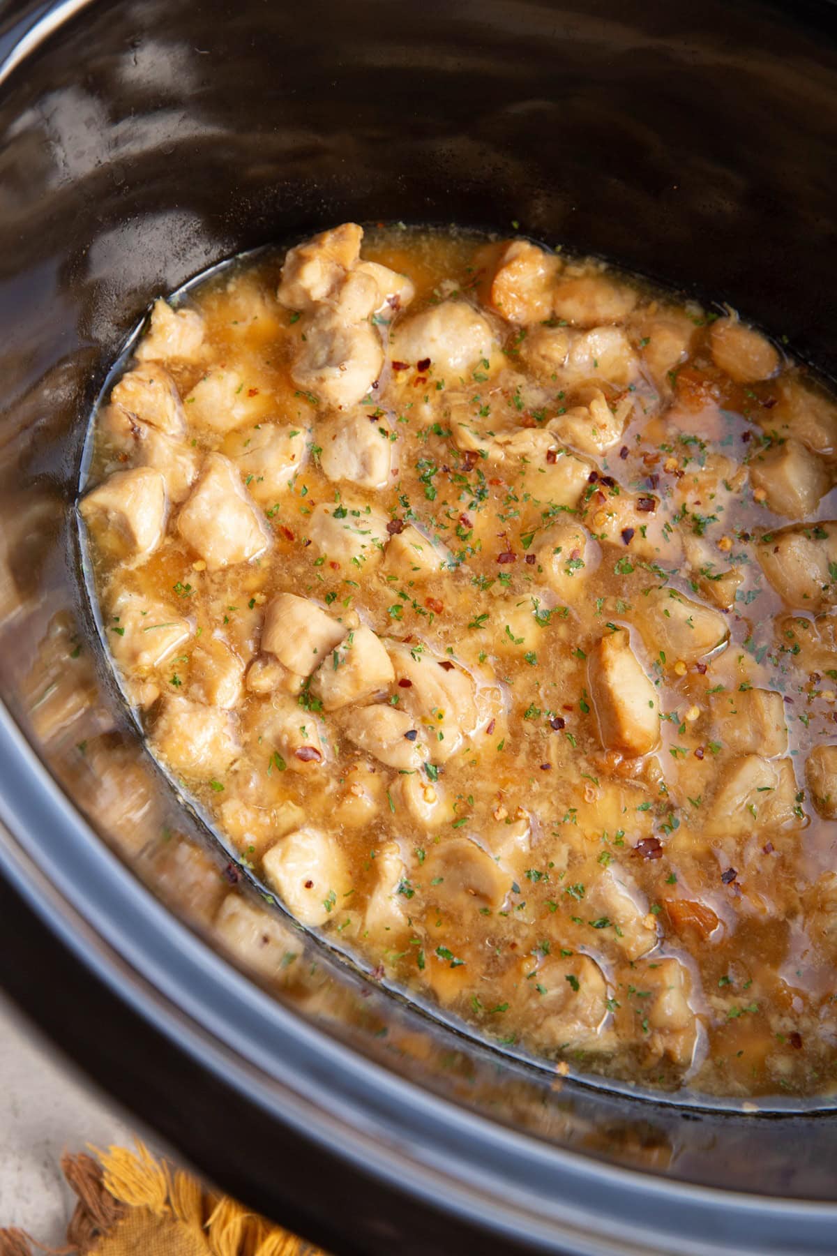 Crock pot full of cooked chicken in sauce.