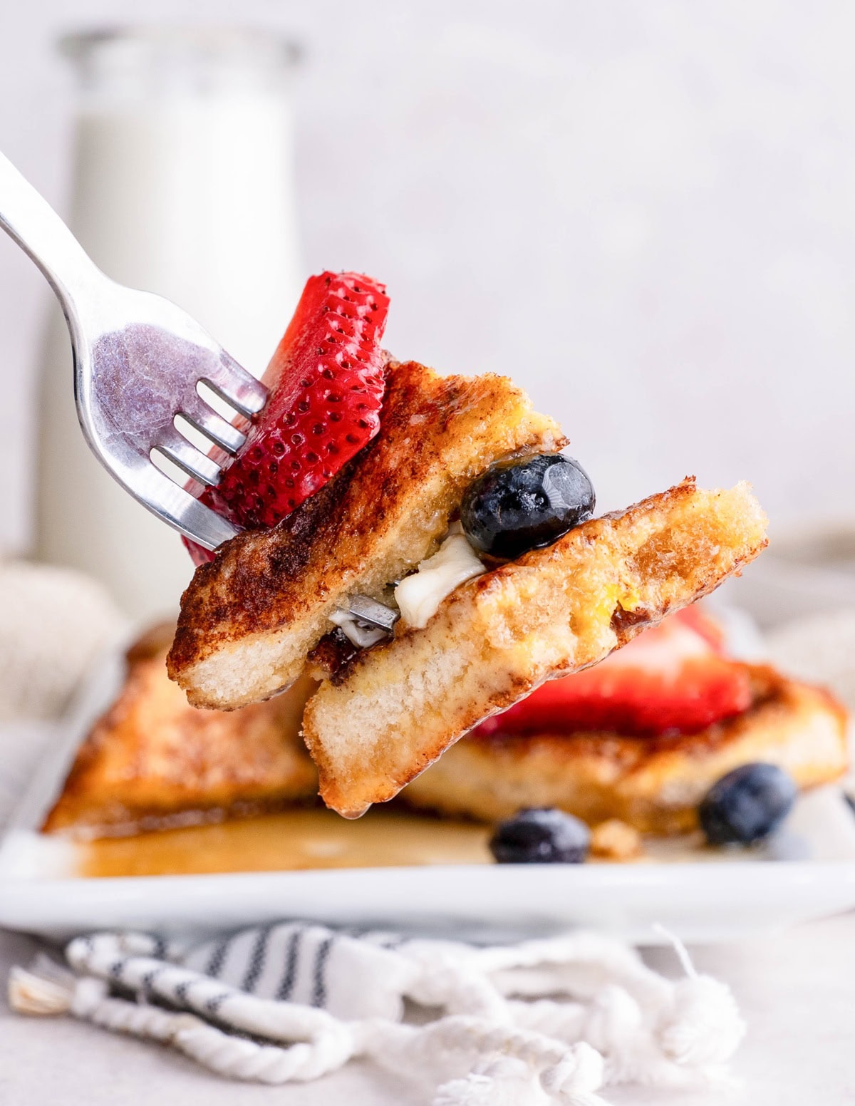 Fork holding a bite of French toast with berries.