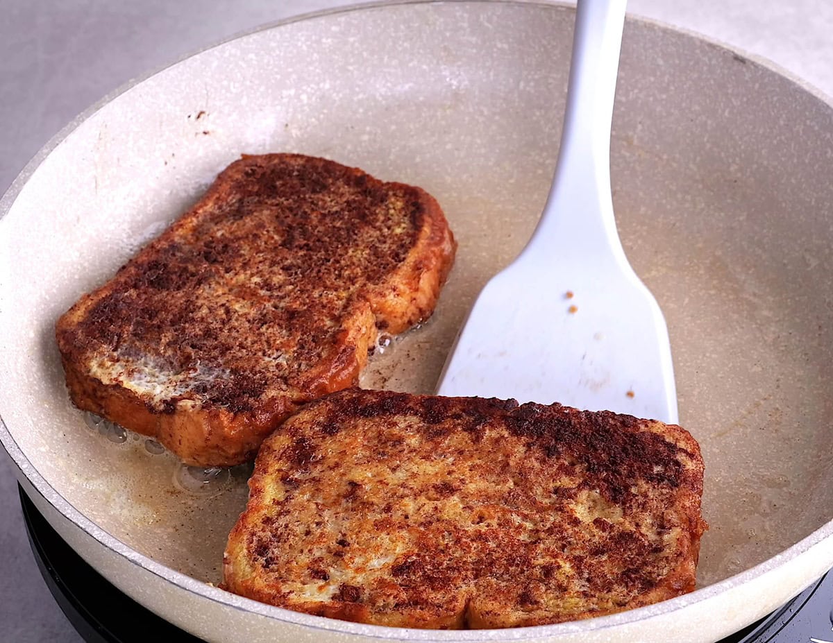 Spatula flipping golden brown toast.