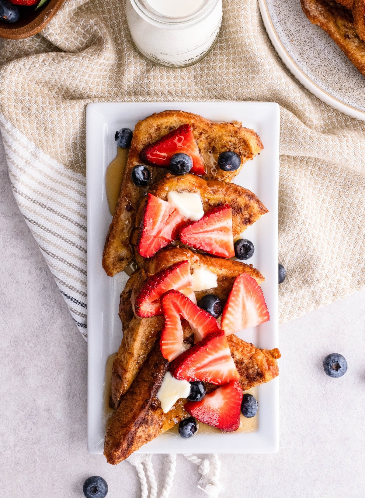 Serving platter with slices of French toast with berries and butter on top. Ready to serve.