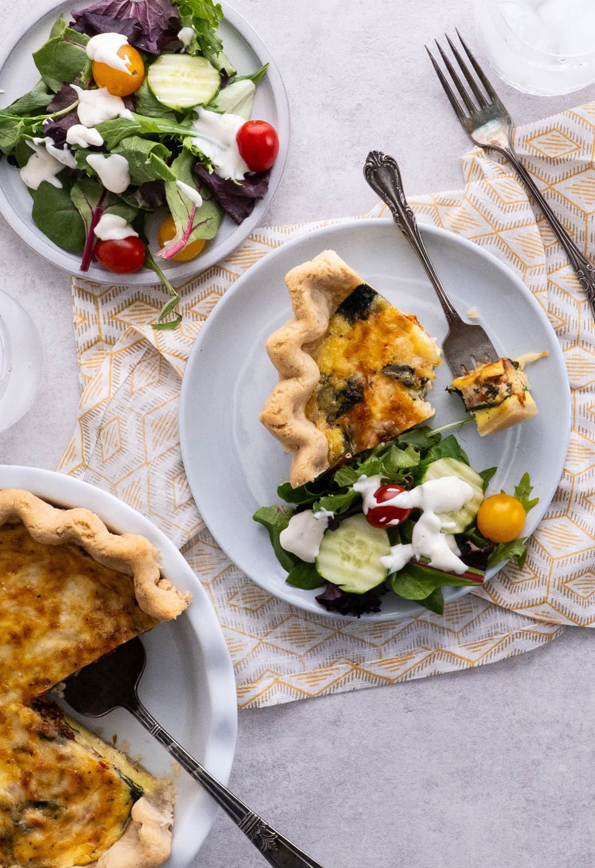 Slice of quiche on a plate with a side salad.
