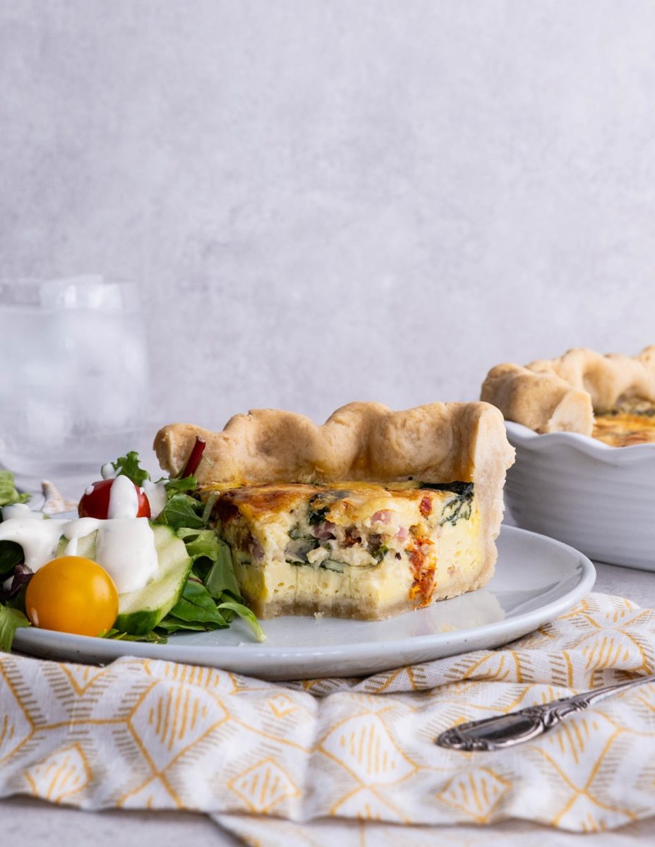 Slice of quiche with a bite taken out.