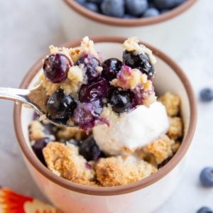 Spoonful of almond flour blueberry crisp scooping to enjoy a bite.