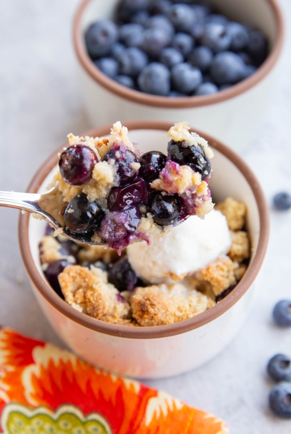Spoonful of almond flour blueberry crisp scooping to enjoy a bite.