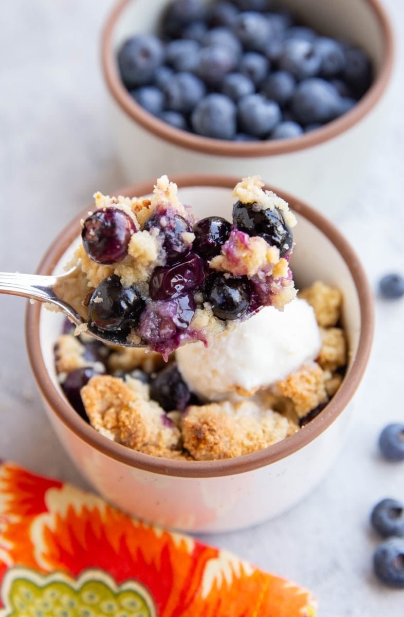 Spoonful of almond flour blueberry crisp scooping to enjoy a bite.