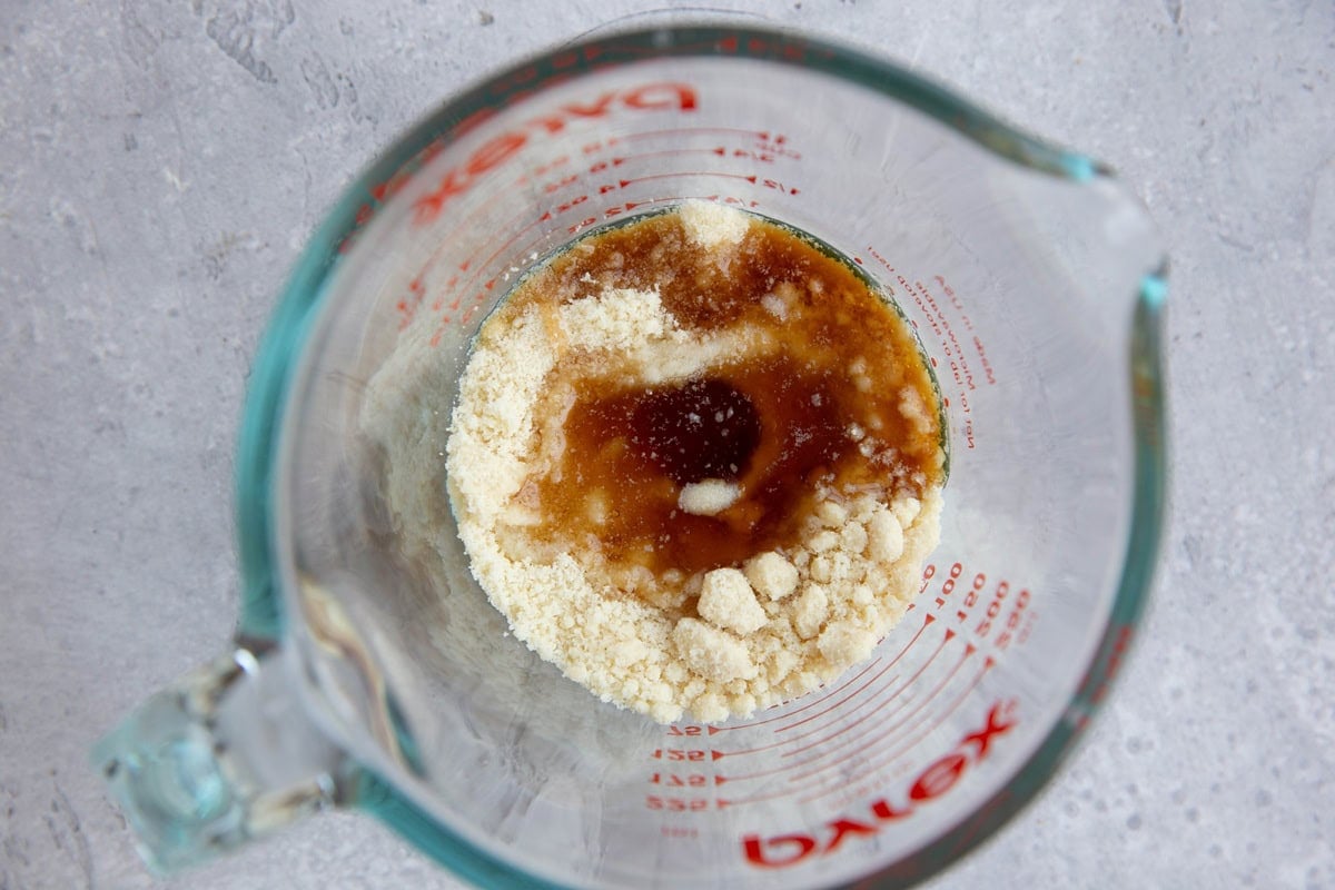 Measuring cup full of crisp topping ingredients to make blueberry crisp.