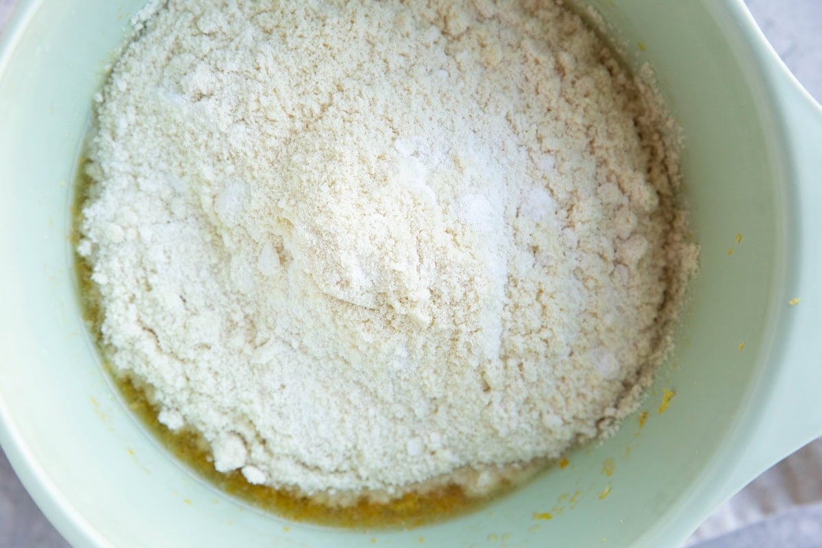 Flour mixture on top of wet mixture in a mixing bowl.