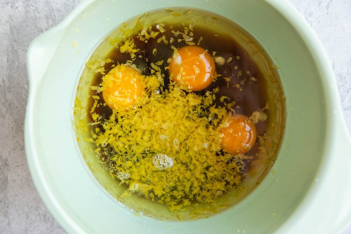 Mixing bowl full of eggs, pure maple syrup, oil, lemon juice, and lemon zest.