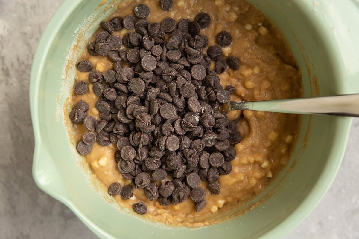 Bread batter in a mixing bowl with chocolate chips added in.