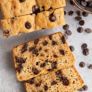 Almond flour chocolate chip bread cut into slices on a background with chocolate chips all around.