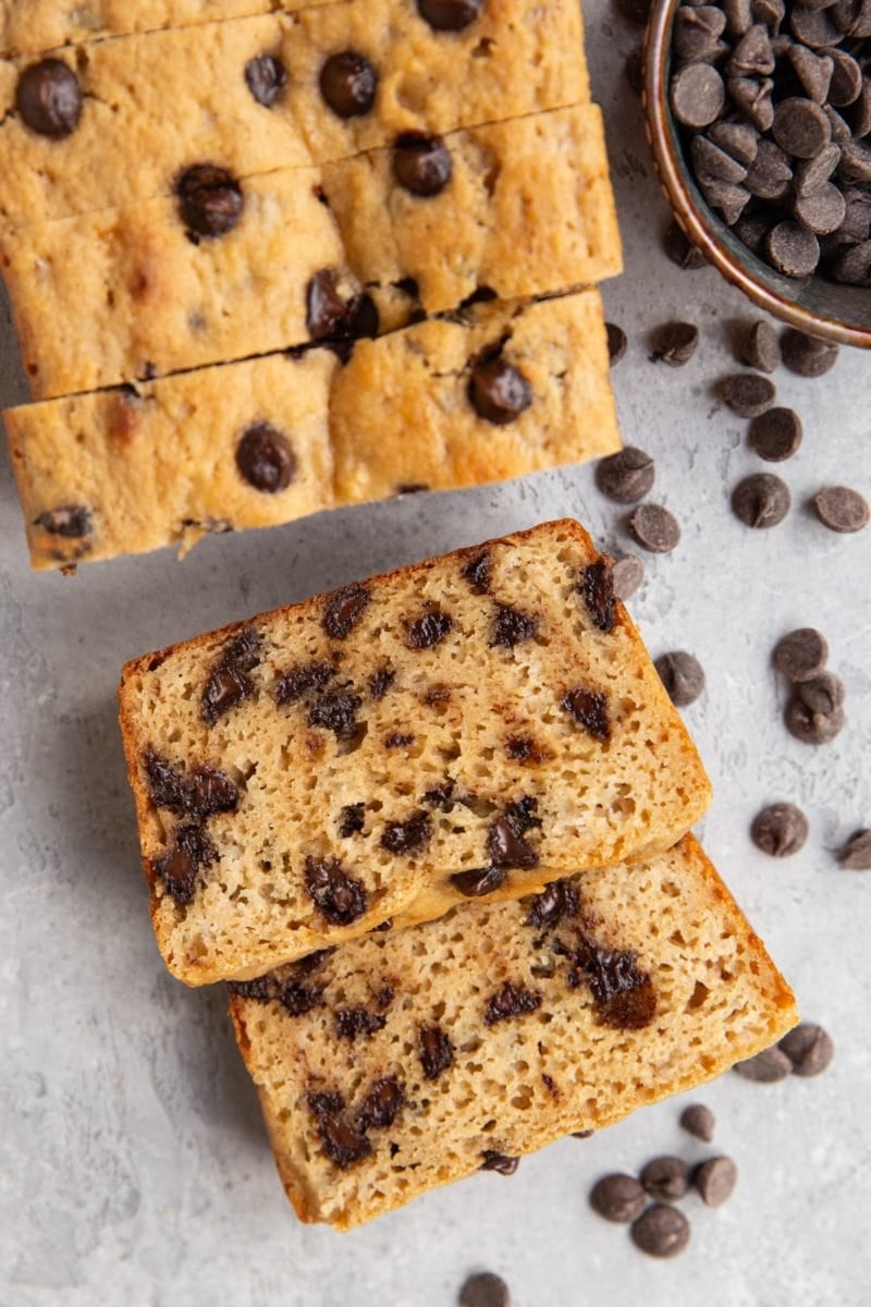 Almond flour chocolate chip bread cut into slices on a background with chocolate chips all around.