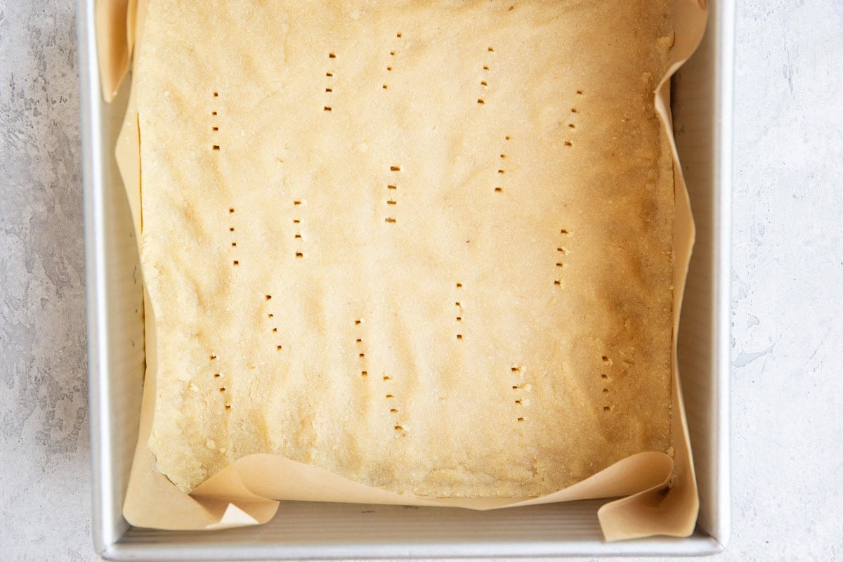 Baking dish with a layer of almond flour crust poked with holes, ready to go into the oven to pre-bake.
