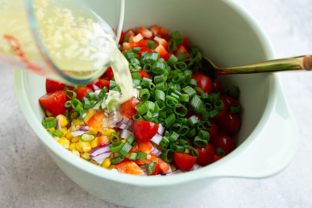 Pouring the dressing for the salad into the bowl with salad ingredients.