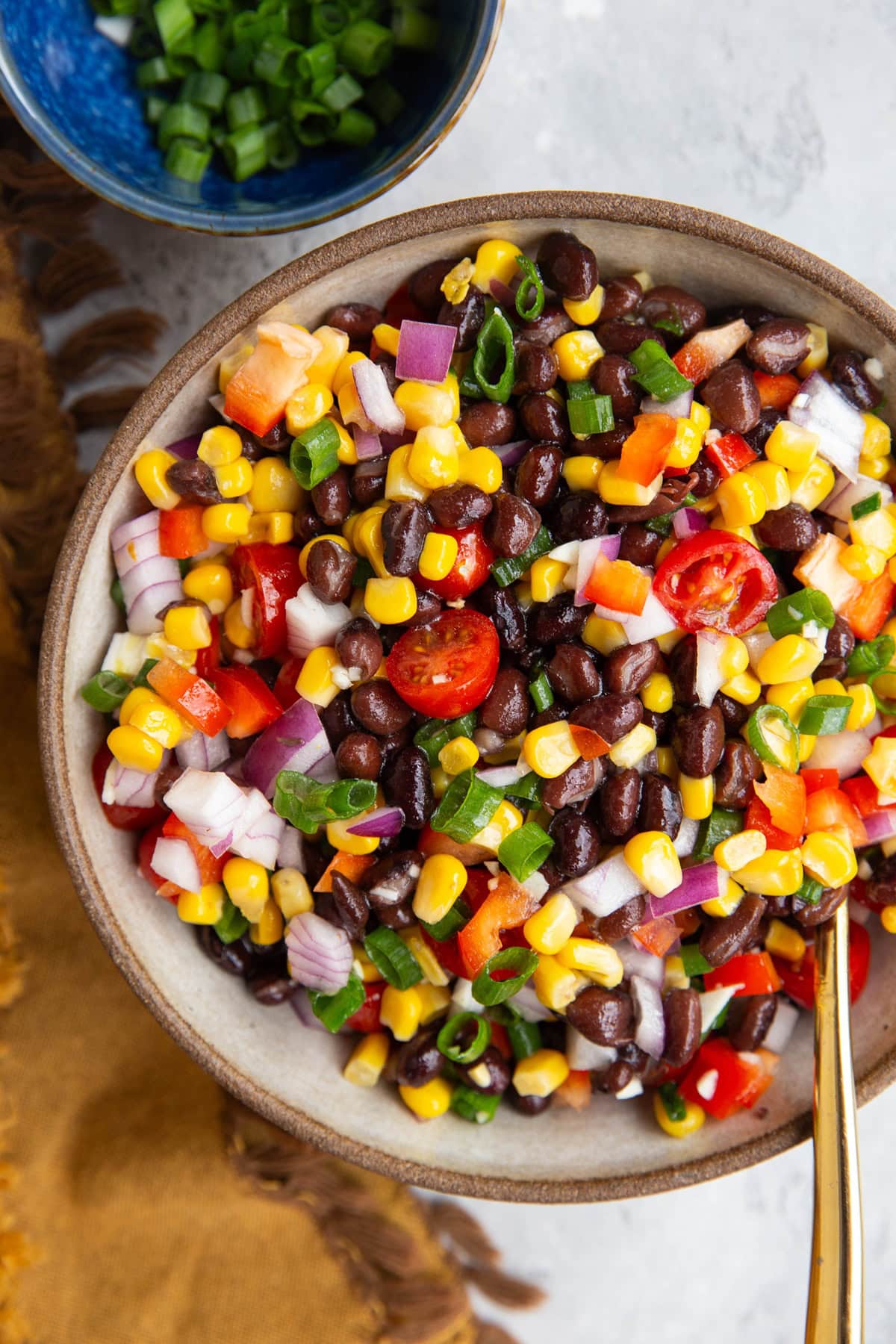 Bowl of black bean salad with onions, tomatoes, and corn.