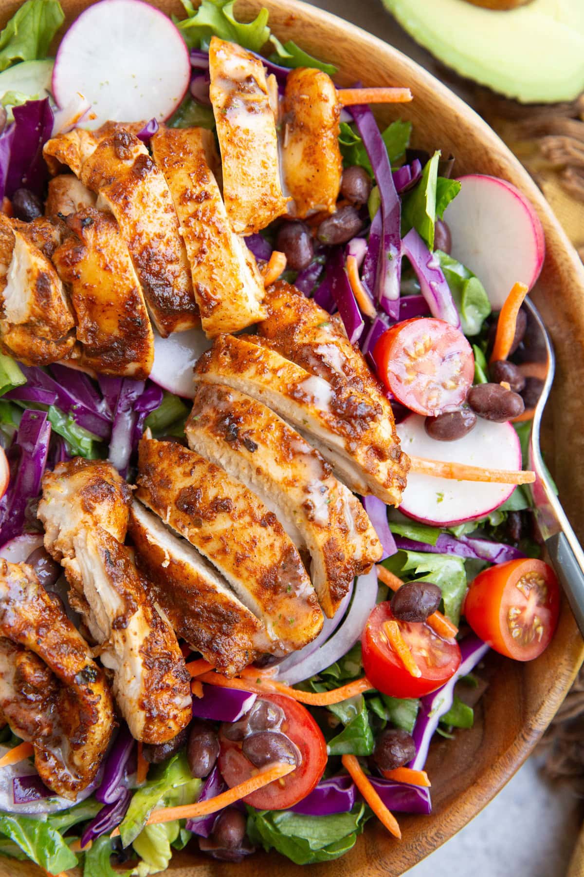 Chicken taco salad in a large bowl with a fork. Fresh vegetables included in the taco salad.