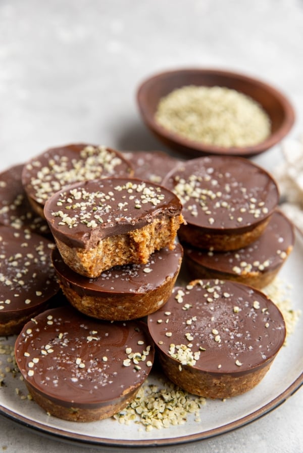Stack of energy bites on a plate. One of the cups has a bite taken out to show the inside.