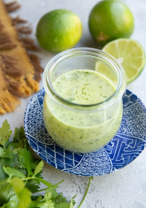 Cilantro lime dressing in a jar on top of a blue plate