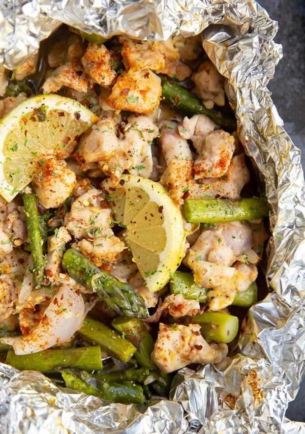 Foil packet of chicken and asparagus on a large baking sheet.