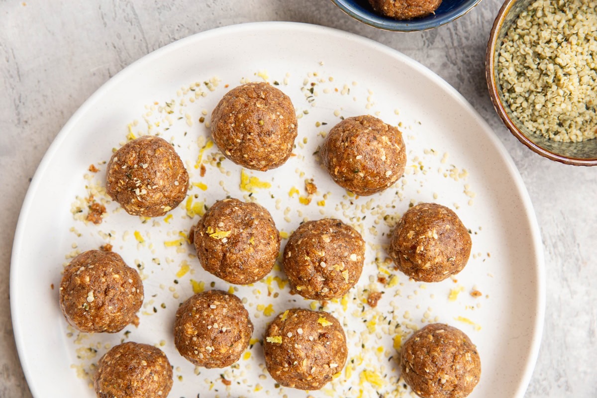 Plate full of protein bites and a bowl of hemp seeds to the side.