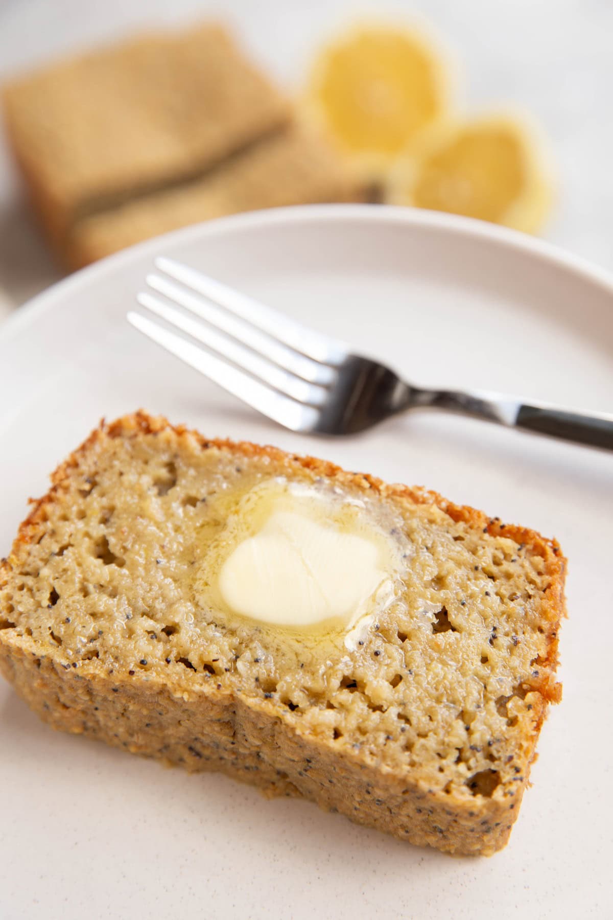 Slice of lemon poppy seed bread on a plate with melted butter. Ready to eat.