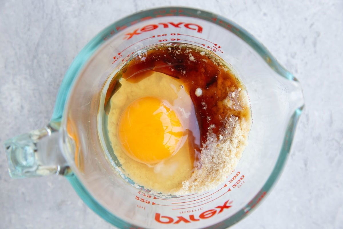 Measuring cup with egg, pure maple syrup and almond flour to make a muffin.