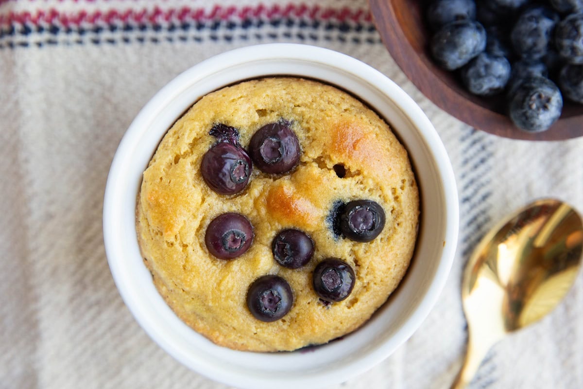 Blueberry muffin in a ramekin with blueberries on top.