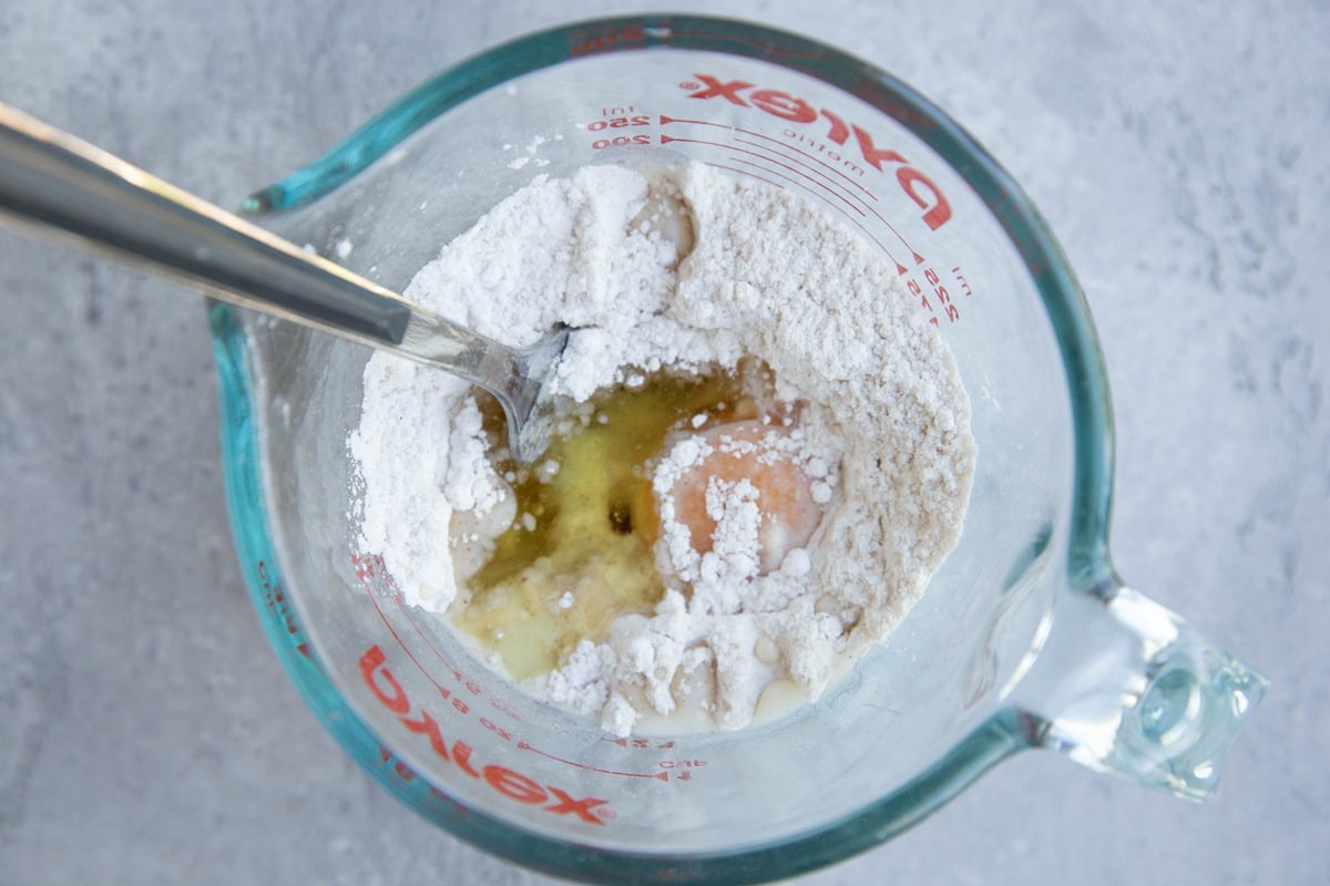Dry ingredients in a measuring cup with oil and egg yolk added in.