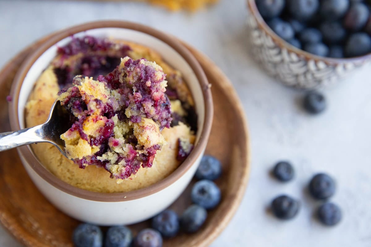 Spoon holding a big bite of blueberry muffin.