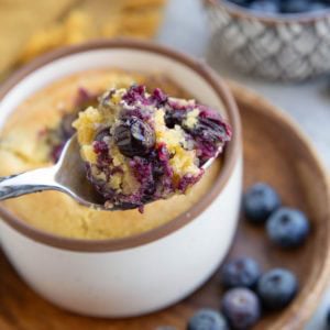 Spoon holding a scoop of blueberry muffin, ready to eat.