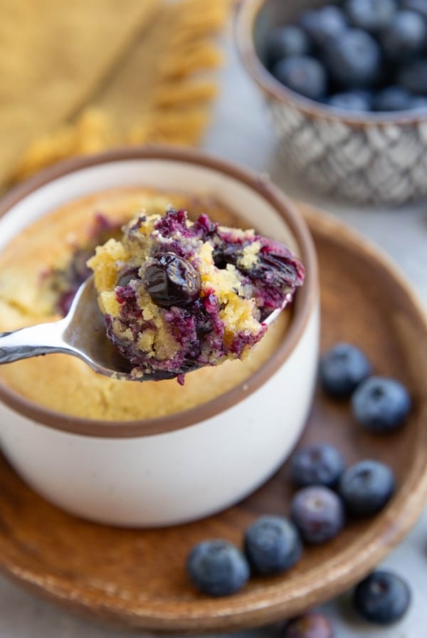 Spoon holding a scoop of blueberry muffin, ready to eat.