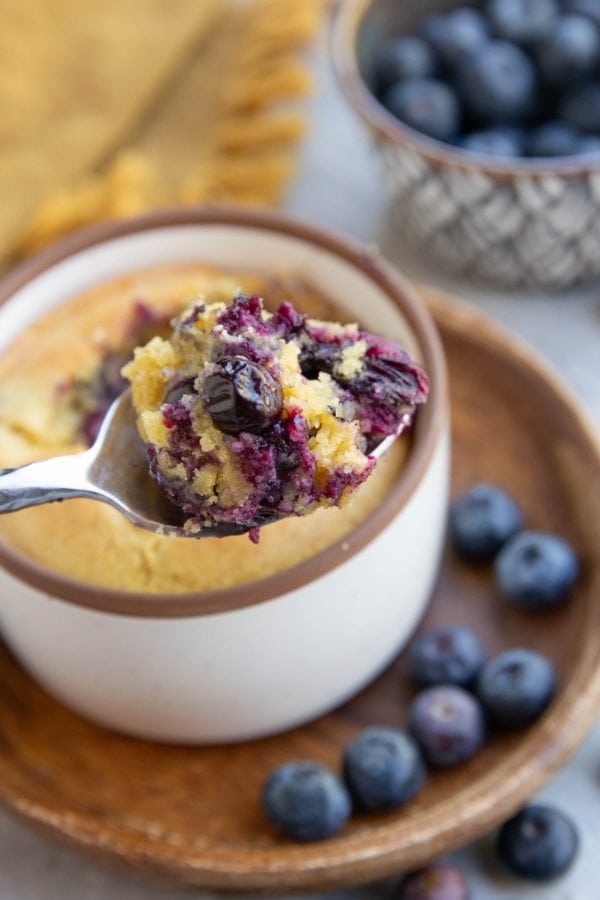 Spoon holding a scoop of blueberry muffin, ready to eat.