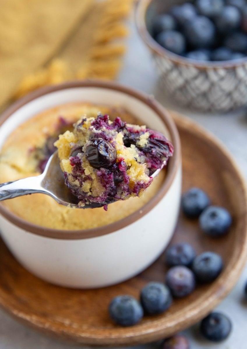 Spoon holding a scoop of blueberry muffin, ready to eat.